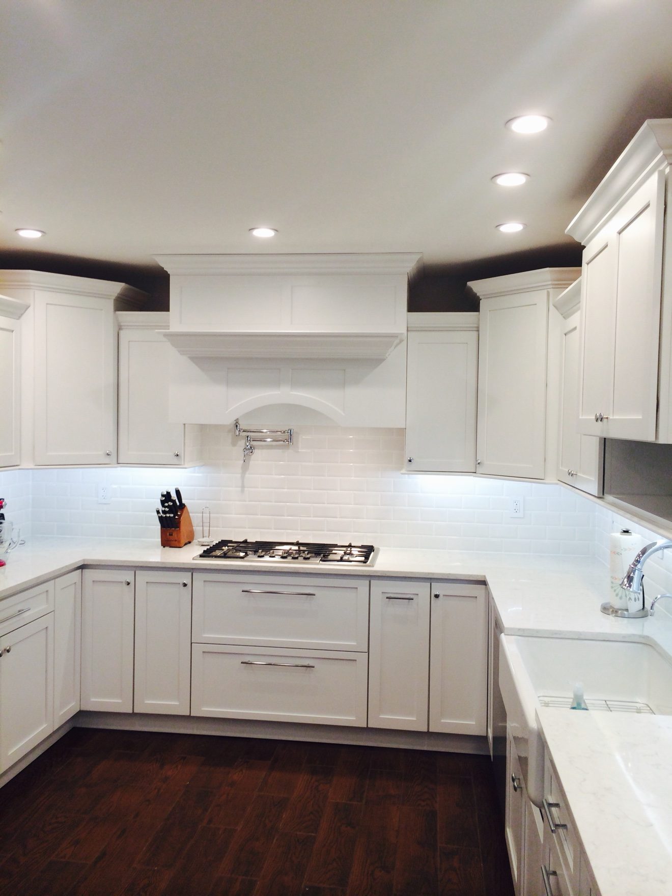 Kitchen — white shaker cabinets, custom range hood, and farmhouse sink.